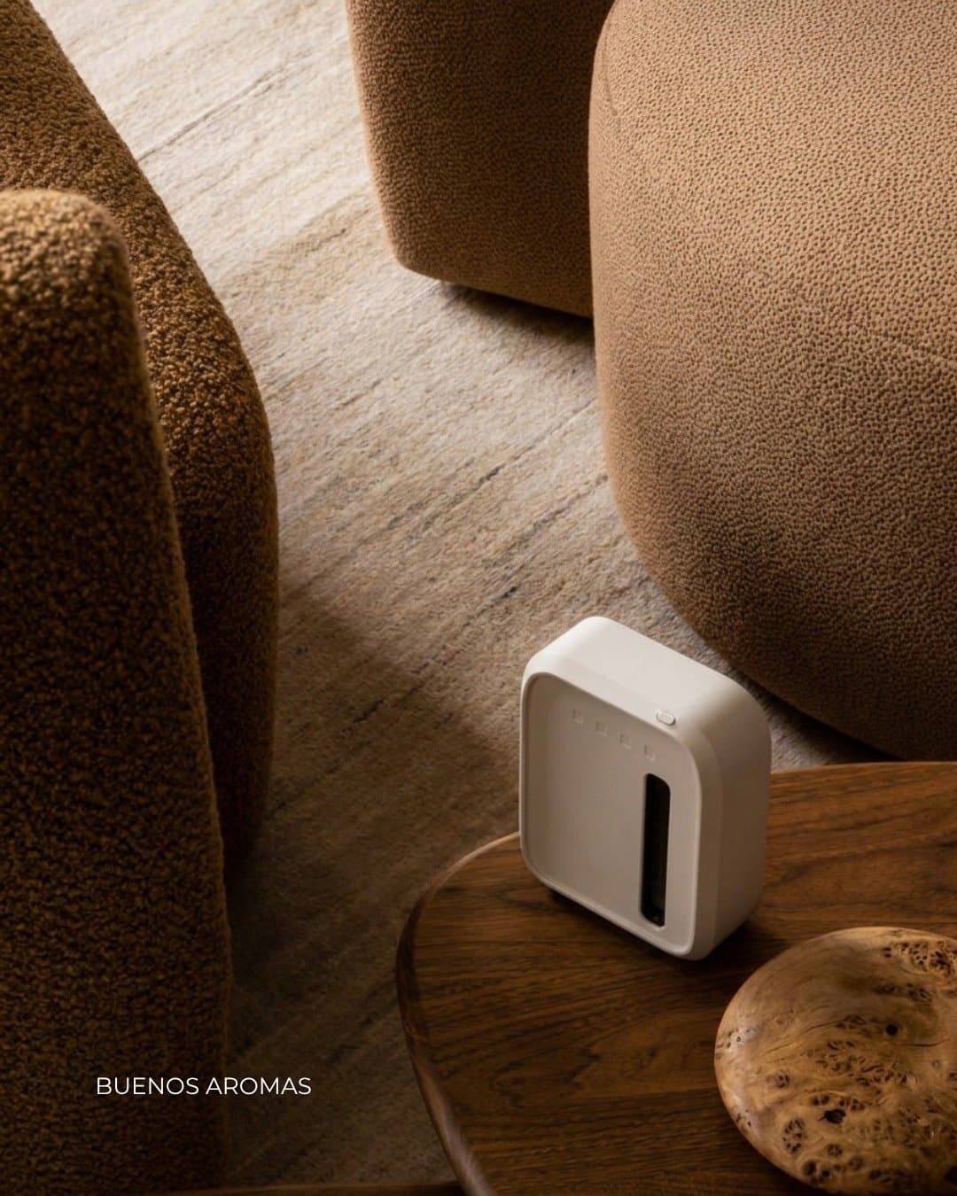 Equipo aromatizador chico sobre una mesa ratona de madera, entre sillones de boucle